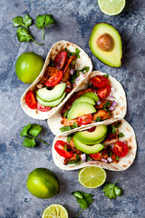 Mexican grilled chicken tacos with avocado, tomato, onion on rustic stone table. Recipe for Cinco de Mayo party. Top view, overhead, flat lay.