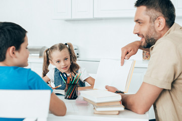 smiling father and kids doing homework together at home