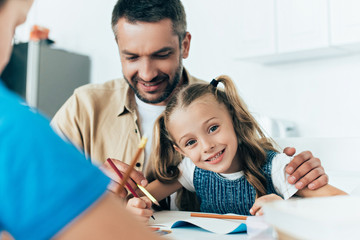 smiling father and kids doing homework together at home