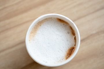 Top view of takeaway  paper cup of hot coffee latte on wooden table..