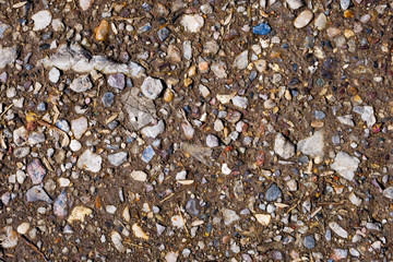 Close up of crushed small stones gravel in brown ground. For texture and background
