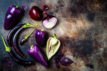 Raw purple seasonal vegetables over rustic background. Top view, flat lay, copy space