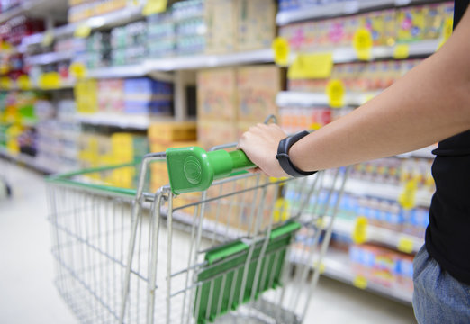 Closeup hand pushing shopping cart in groceries store