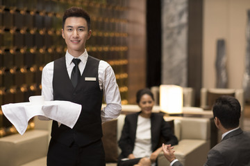 Cheerful young waiter serving coffee