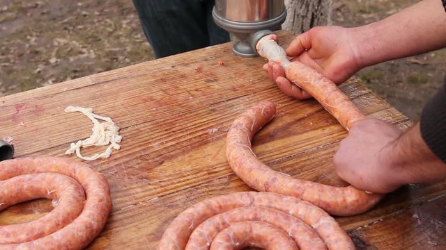 Butcher is stuffing pig intestine with minced meat to make sausages. Fill up pig intestines to make sausage with machine for handmade sausages.