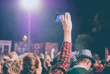 Young woman recording concert by mobile phone