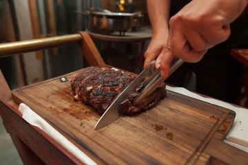 Cutting grill beef on wooden cutting board in the restaurant for dinner.