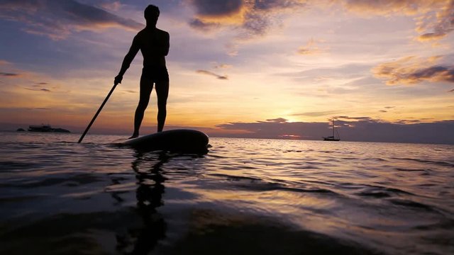 SUP, paddleboard on the beach at sunset, paddle standing in Thailand