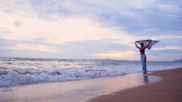 Silhouette attractive young asian woman with sunglasses running on beach holding waving scarf on beautiful windy with twilight in sunset,Slow motion footage