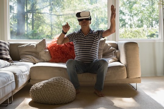 Man using virtual reality headset while sitting on sofa at home