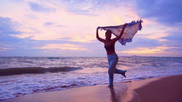 Silhouette attractive young asian woman with sunglasses running on beach holding waving scarf on beautiful windy with twilight in sunset,Slow motion footage