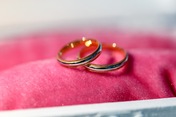 A close-up shot of expensive gold wedding rings on pink pillow. Gold Wedding rings on a pillow on pink