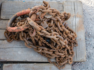 Rusty chain on weathered squared timber.