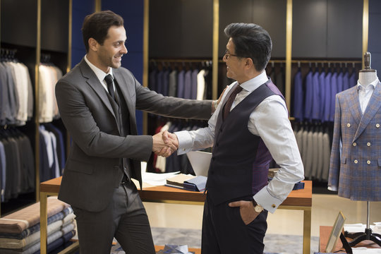 Confident fashion designer shaking hands with businessman