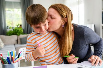Proud mother teaching child at home how to write. Early education