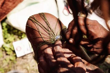 Street jewelry artist hands creating jewelry from labradorite stone and wax strings © marbenzu