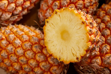 Bunch of fresh pineapples in the organic food market. One pineapple is cutted