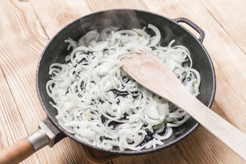 Fried onions in a frying pan. Roasting the chopped onion in oil.