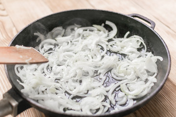 Fried onions in a frying pan. Roasting the chopped onion in oil.