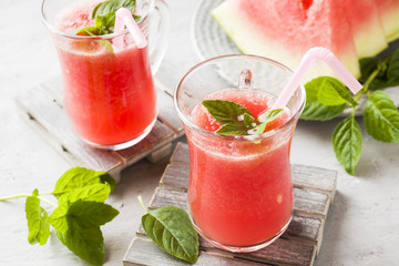 Fresh watermelon smoothie with ice and mint leaves in glasses.