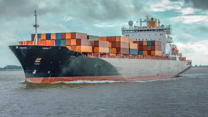 Containerschiff in Fahrt auf der Elbe bei Hamburg