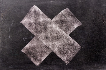 White color chak hand drawing in cross or x shape on blackboard background