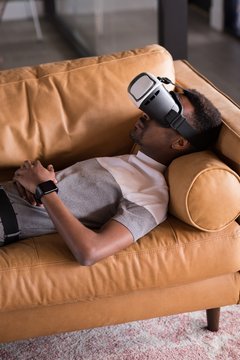 Man experiencing VR headset while lying on sofa