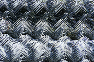 Rolls of galvanized steel wire mesh with a large cell and twisted pattern close-up. In the category of texture, screen saver, wallpaper.