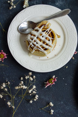 Cinnamon roll with white glazed icing flat lay