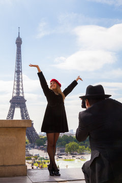 Beautiful Smiling Young Woman Poses with Her Arms in the Air for a Photo in Paris with Eiffel Tower behind Her.