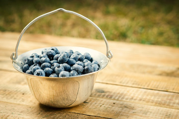 Juicy and blueberries in a container on an old wooden table in the summer