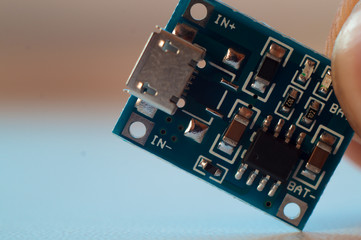 Two fingers holds small microscheme with small details. Close-up view. Image contains informational...