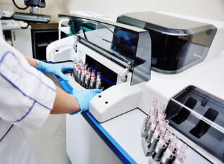 a female scientist near the analyzer in a medical microbiological laboratory. Equipment for...