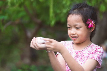 Beautiful asian little girl has fun smile face, happy eyes and lovingly embraces her pet rat.