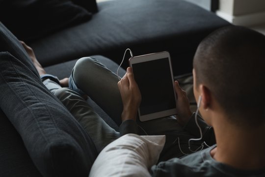 Androgynous young man listening music on digital tablet