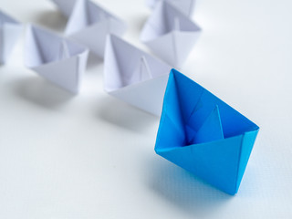 Leadership concept. Blue paper ship lead among white. One leader ship leads other ships.
