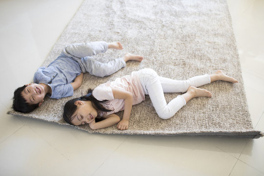 Cute children lying on carpet in new house