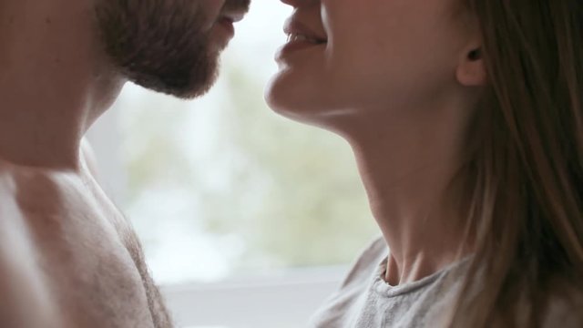 Handheld shot with close up of happy young woman and bearded man with bare chest rubbing their noses and smiling