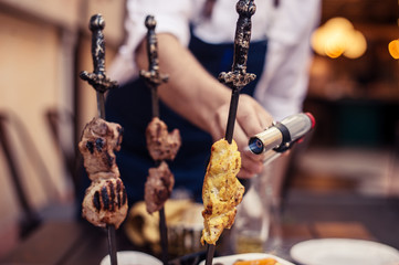 Meat on skewer fry with a cooking gas torch flomber.