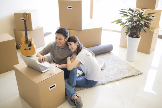 Young couple using laptop in their new house