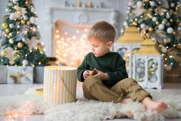 little boy opened the box with a surprise on the background of the New Year's decor. New Year's decor