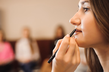 Makeup artist creating beautiful makeup for brunette model