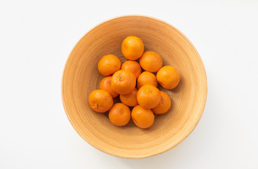 Top down view of orange mandarines in bamboo bowl on white table