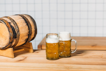 selective focus of mugs with light beer and barrel at bar counter
