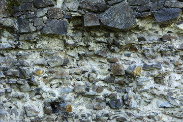 An old faded stone in the cracked weathered and shattered wall of a once majestic castle. In the category of creative background of exotic summer holidays, screen saver, wallpaper.