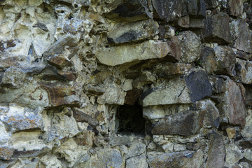 An old faded stone in the cracked weathered and shattered wall of a once majestic castle. In the category of creative background of exotic summer holidays, screen saver, wallpaper.