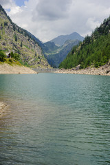 alpine high mountain lake, coniferous woods are reflected in the water, Antrona valley Campliccioli lake, Italy Piedmont