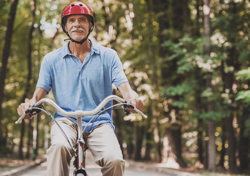 Old Man Riding on Bicycle in Park in Summer .