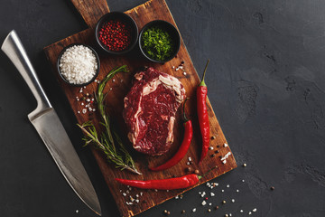 Rib eye steak with spices on wooden desk, closeup