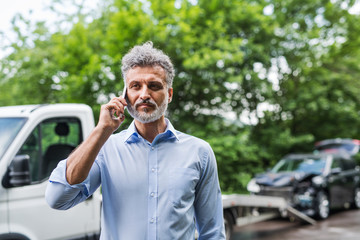 Mature man making a phone call after a car accident. Copy space.